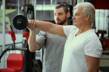 Rehabilitation concept. Mature man doing exercises under physiotherapist supervision