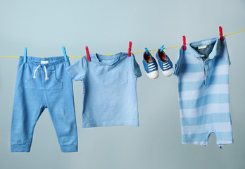 Clothesline with hanging baby clothes on grey background