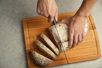 Male hands cutting homemade bread, closeup