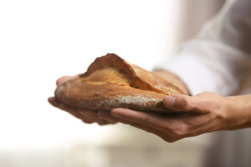 Male hands holding freshly baked rye bread, closeup