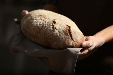 Male hands holding freshly baked rye bread, closeup