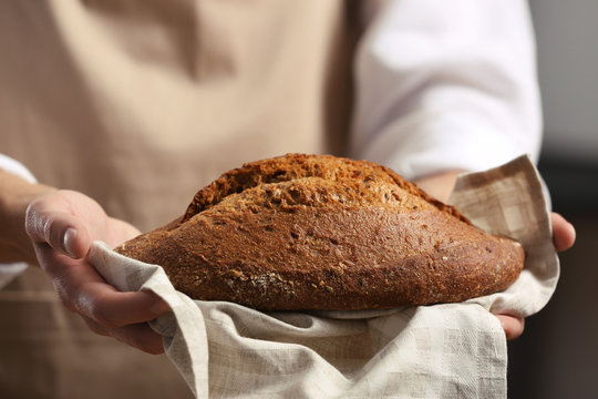 Male hands holding freshly baked rye bread, closeup