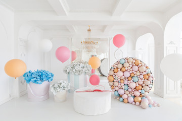 Boxes with flowers and a large pudrinitsa with balls and balloons in room decorated for birthday...