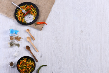 plates with pasta, spoon, chili pepper, spices, fork, sackcloth napkin