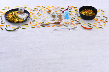 scattered pasta, plates, fork, spoons, chili pepper, spices