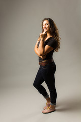 Fototapeta premium Young mixed race woman wearing a black t shirt and jeans stands confidently with hair blowing and hand on chin while smiling at viewer