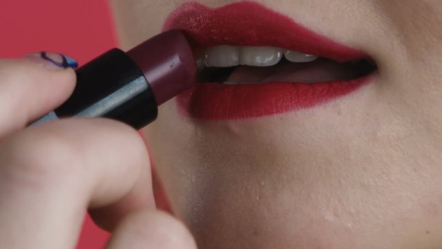 girl paints her lips close-up