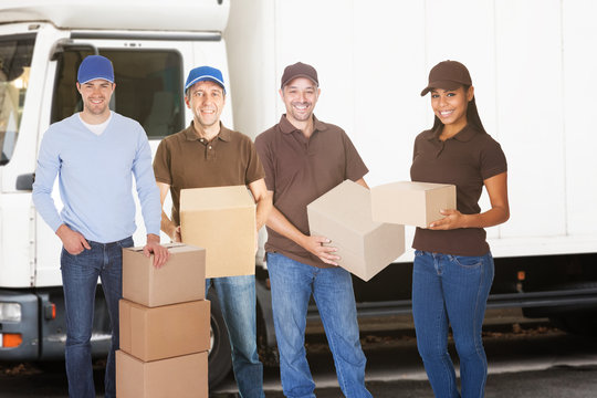 Group Of Delivery People Standing With Boxes