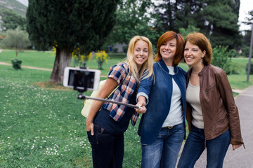 Young women friends taking a selfie using selfiestick. Remember girl time