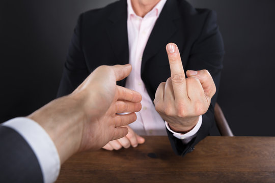 Businessman Showing Middle Finger To A Partner