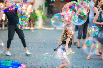 Adorable little girl blowing soap bubbles in Trastevere in Rome. Happy kid enjoy summer vacation in...