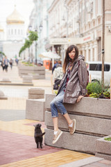 beautiful woman walking with a cat in the city