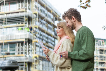 Fototapeta premium Couple with blueprint project keys on construction site