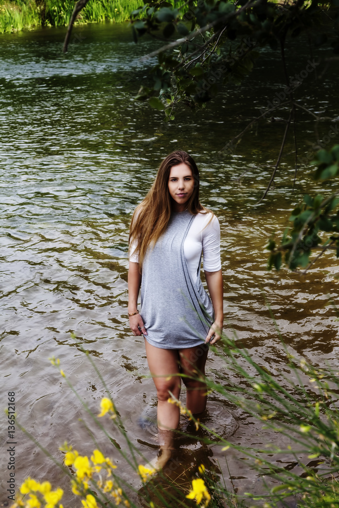 Wall mural attractive caucasian teen woman standing in river