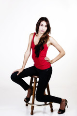 Skinny Latina Woman Sitting On Stool Red Top Blue Jeans