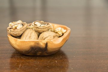 Walnuts in a wooden bowl on an antique table