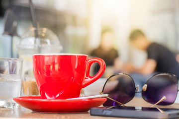 Red coffee cup with smart phone on wooden table
