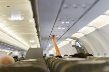Passenger hand adjusting overheaded electronic inside airplane. Closeup