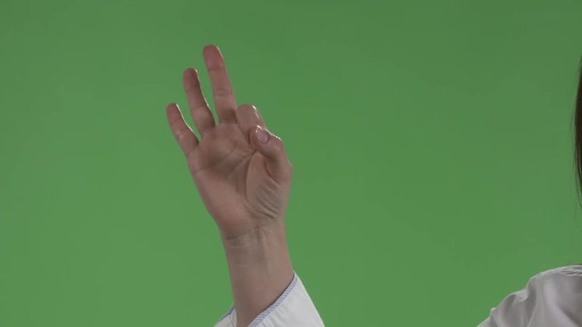 Close-up of female hand showing ok sign against a green screen