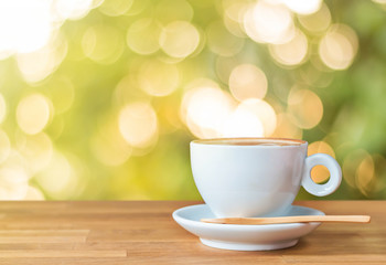A cup of coffee on wood table with light and bokeh background