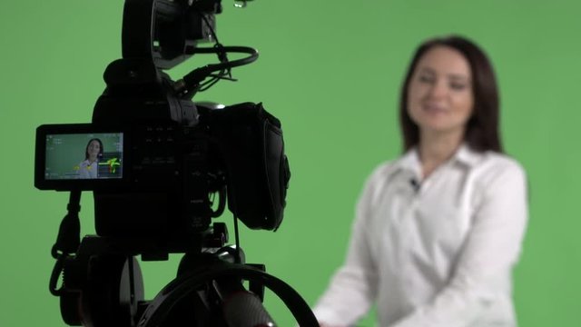 Recording an interview in virtual green chroma key studio woman talking in front of camera