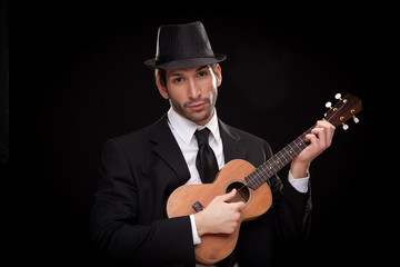 Obraz premium elegant happy man singer musician playing ukulele guitar isolated on black