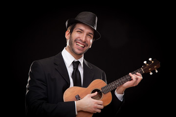 elegant happy man singer musician playing ukulele guitar isolated on black