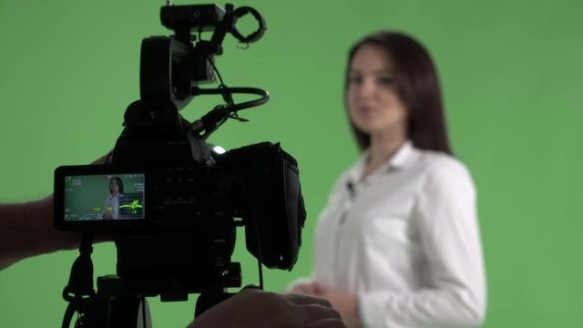 Recording in virtual green chroma key studio woman talking to camera presenting and showing something