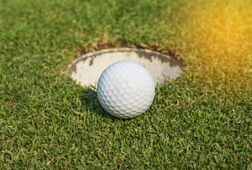   golf ball on lip of cup on green grass 