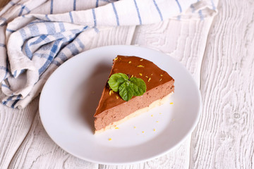 Chocolate cheesecake, decorated mint on a white plate