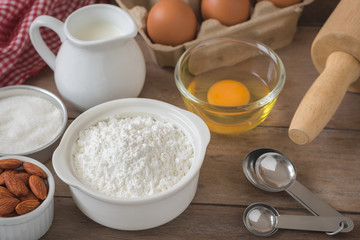 Baking ingredients flour, egg, milk, almonds, sugar on table