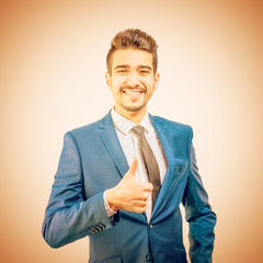Young attractive man in a blue suit showing thumb up. Toned