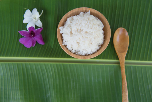 Top View Cooked Rice In Bowl On Green Banana Leaf Spoon And Orchid .