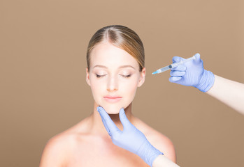 Doctor injecting botox in a beautiful face of a young woman. Pla