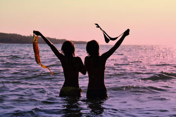 Fototapeta premium Two girls in ocean at sunset 