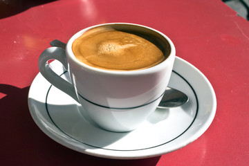 Hot espresso macchiato - cafè with a little milk. White coffe cup on outdoors table. Taken in Madrid