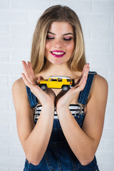 portrait of beautiful female model in jeans and toy car in her hands