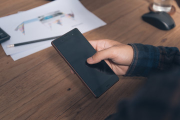 hand using phone on worktable