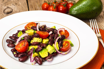 Salad with beans and avocado on background of old boards