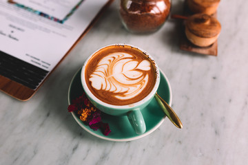 A blue cup of coffee with jar of sugar on a marble table