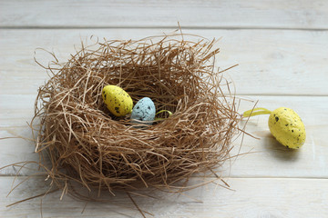 Colorful Easter eggs in the nest of a bird on a wooden board.