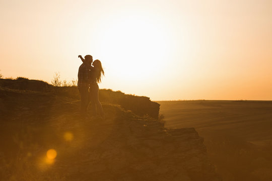 Man and woman tourists in the mountains at sunset. Happy couple in love.