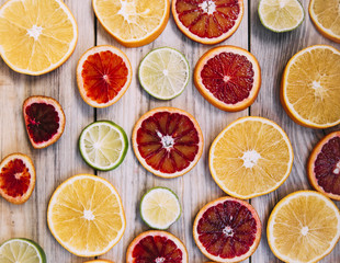 Juicy fresh plain and blood oranges and lime slices on the wooden table background,flat lay view 
