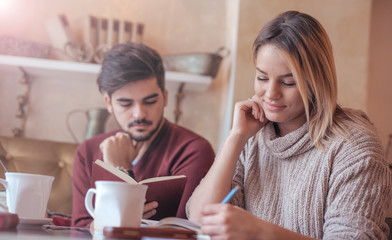 Young couple drinking coffee and reading a book in the cafe. Edu