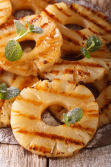 grilled pineapple with mint and powdered sugar close-up on the table. vertical