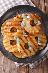 Delicious grilled pineapple with mint close up on a plate. vertical top view