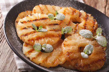 Fresh grilled pineapple rings with mint close up on a plate. horizontal