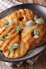 Delicious grilled pineapple with mint close up on a plate. Vertical