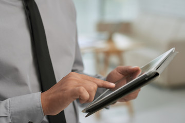 Close-up shot of male hands using digital tablet, blurred background