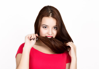 beautiful young woman dressed in a red dress, holds and bites pigtails. studio shot